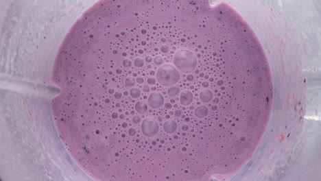 mixed berry smoothie blender bowl close up top view. organic milkshake preparing