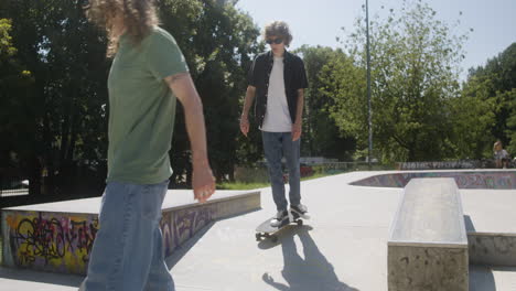 boy explaining a trick to his friend in skatepark.