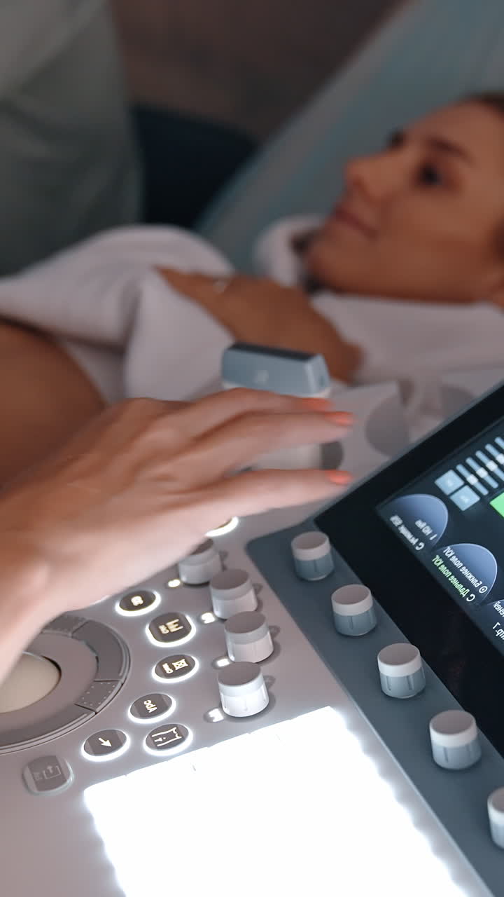 Doctor's hand operating ultrasound machine for pregnant lady examination. Medic moves the sensor by the belly of Caucasian woman. Vertical video