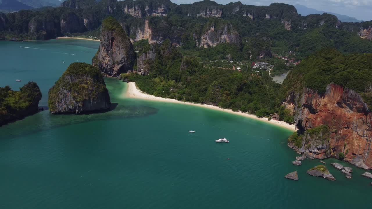 Beautiful aerial view of Railay Beach near Ao Nang, Thailand, showing limestone cliffs, turquoise sea, palm trees, and a laid-back tropical coastline only accessible by boat.