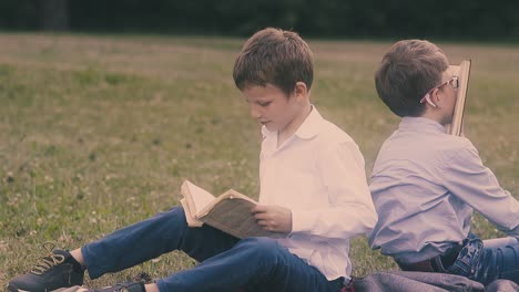 concentrated-boy-sits-in-green-garden-near-school-mate