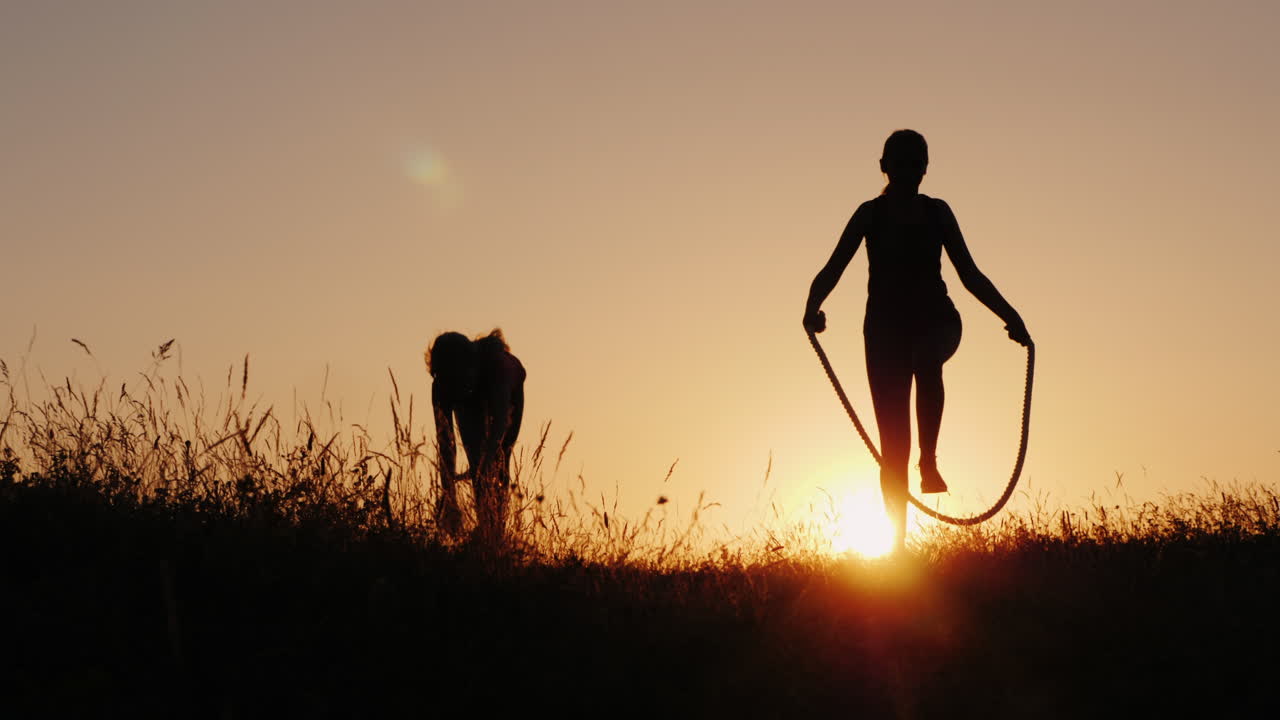 entrenando al aire libre - una silueta de una mujer saltando sobre una cuerda al atardecer