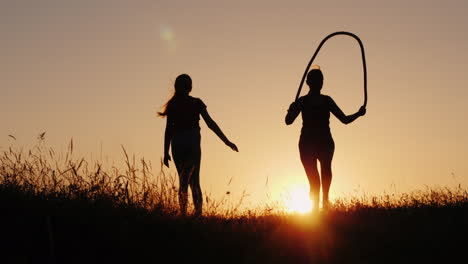 training in the fresh air - a silhouette of a woman jumping over a rope at sunset