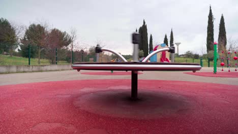 Empty-playground-during-Covid-19-coronavirus-pandemic-lockdown,-carousel-spinning-on-its-own