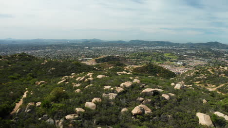 flying over open space with boulders and chaparral towards developments in escondido, ca