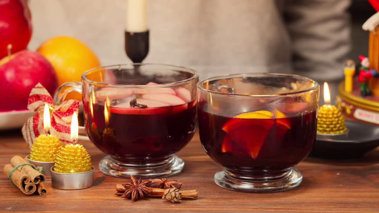 Glühwein mit Zimtstange in gemütlicher festlicher Umgebung umrühren