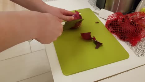 mujer caucásica cocinando y cortando cebolla morada