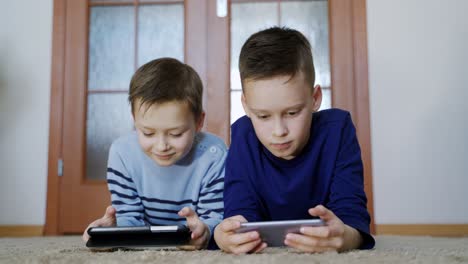 cute little brothers playing games at smartphone. children use gadgets
