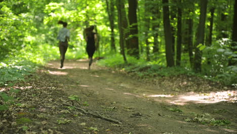 back view of two sportswomen running in the woods