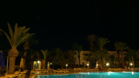 night swimming pool with lighting and palm trees in luxury time lapse