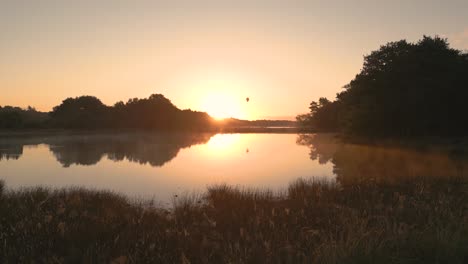 sunrise over a lake with hot air balloon