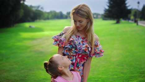 Happy-family-spending-sunset-time-in-garden.-Mother-looking-to-daughter-outdoor.