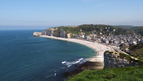 Weitwinkelaufnahme-Der-Stadt-Etretat-Mit-Sandstrand-Und-Meeresklippen-Im-Hintergrund-An-Einem-Sonnigen-Tag-In-Frankreich-–-Malerische-Landschaft-Mit-Blauem-Himmel-–-Schwenk