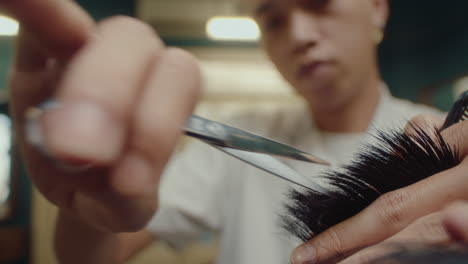 hands of barber trimming hair with shears
