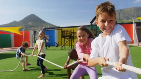 Vorderansicht-Von-Gemischtrassigen-Schulkindern,-Die-Auf-Dem-Schulhof-Tauziehen-Spielen,-4k