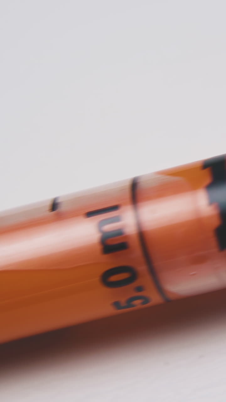 new plastic syringe with orange element and measuring scale lies on white background extreme close view