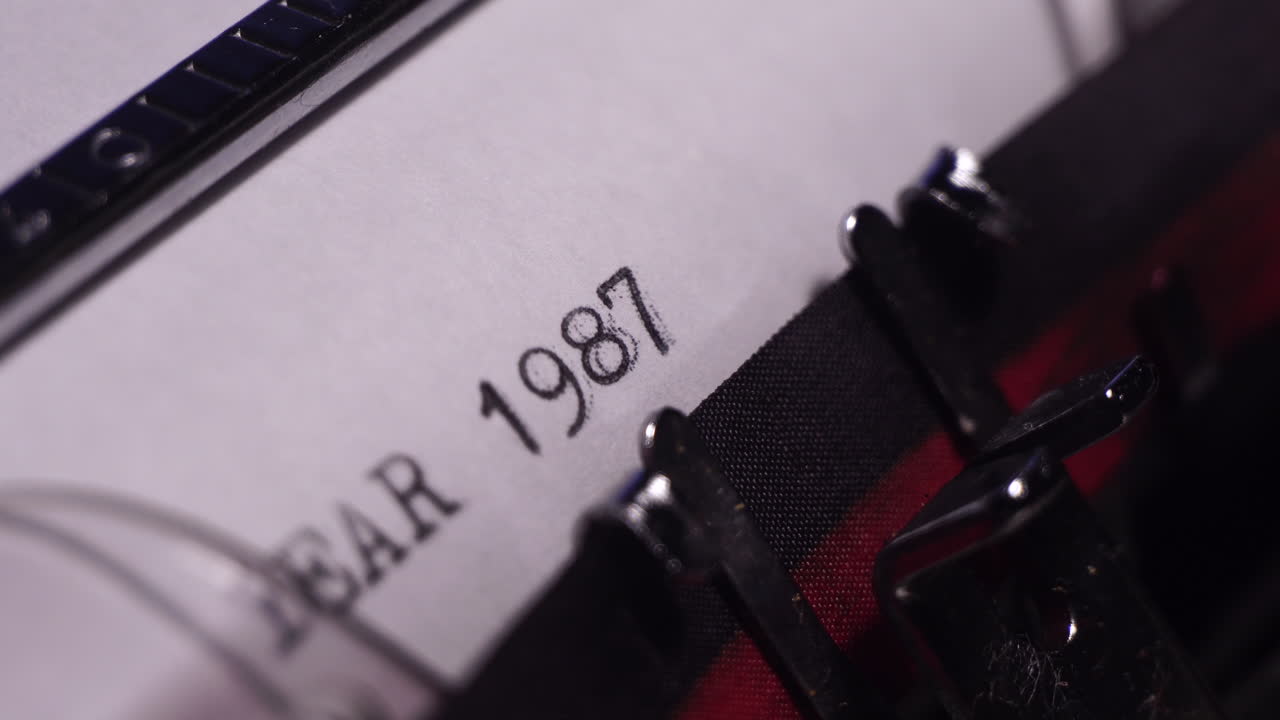 año 1987, escribiendo en papel blanco en una máquina de escribir de época, de cerca