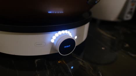 hand of a woman operating control button of induction cooker