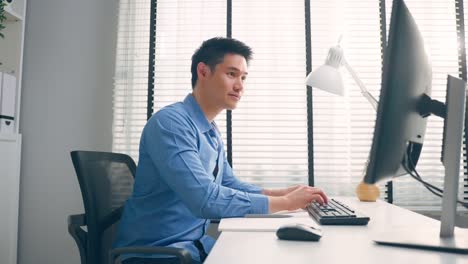 asian handsome business man using laptop computer working in office. attractive professional male employee worker sitting on table, feel happy and enjoy spending leisure time in corporate workplace.