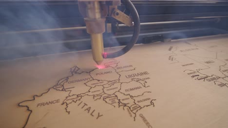 cnc laser cutting machine cuts world map on wooden plank and plywood