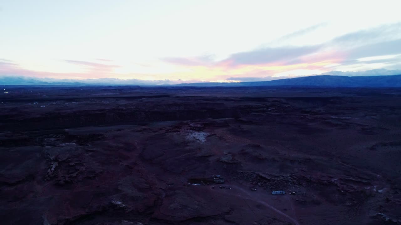Faint morning light reveals rocky desert landscape under calm pastel sky at golden hour