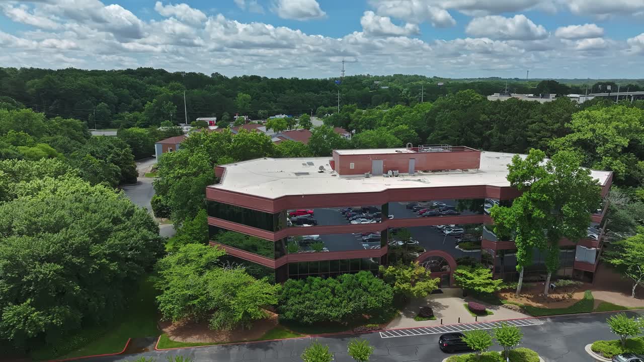 Modern office building with red brick and mirrored windows in American suburb town. Green trees in summer. Aerial view