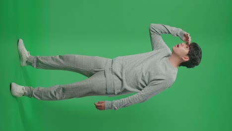 full body of asian man looking at something while standing in front of green screen background
