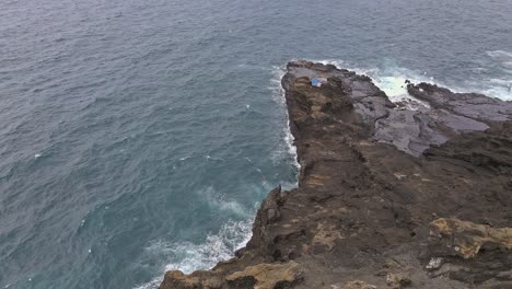 aerial view of cliff revealing rocky point in hawaii tracking forward