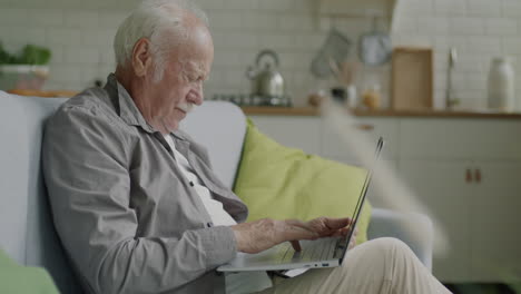 hombre mayor usando computadora portátil en casa