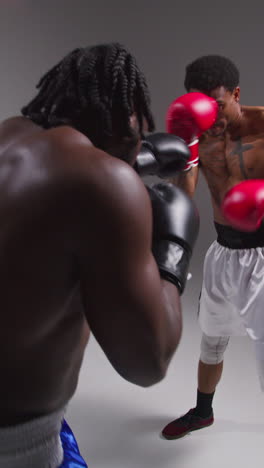 disparo de estudio de video vertical de dos boxeadores masculinos con guantes luchando en un partido de boxeo disparado en tiempo real