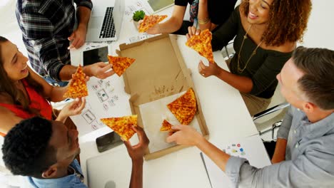 ejecutivos felices compartiendo pizza en la sala de conferencias en la oficina