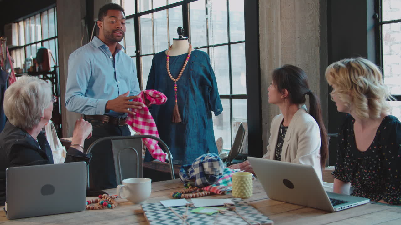 네 명의 패션 디자이너 들 이 옷 을 논의 하고 있다