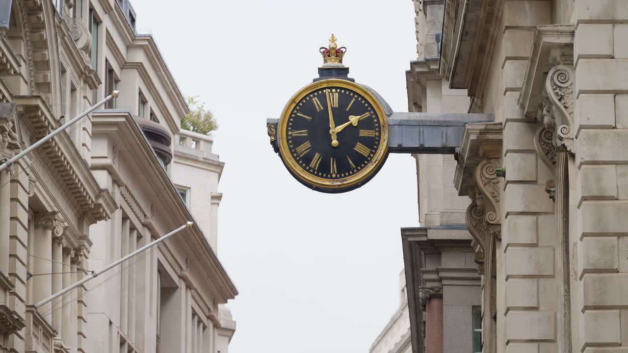 Close-up of a decorative black and gold clock mounted on a historic stone building in London, England