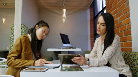 Executives-discussing-over-a-digital-tablet-in-office-cafeteria-4k