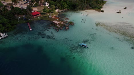 Aerial:-over-the-beach-and-turquoise-ocean-water-in-Bacalar,-Mexico