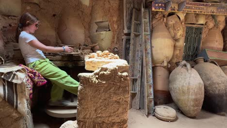 young potter female apprentice at work with clay in rural workshop