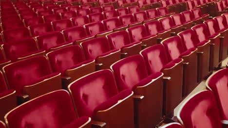 wide shot passing by empty red audience seats in an empty public theatre