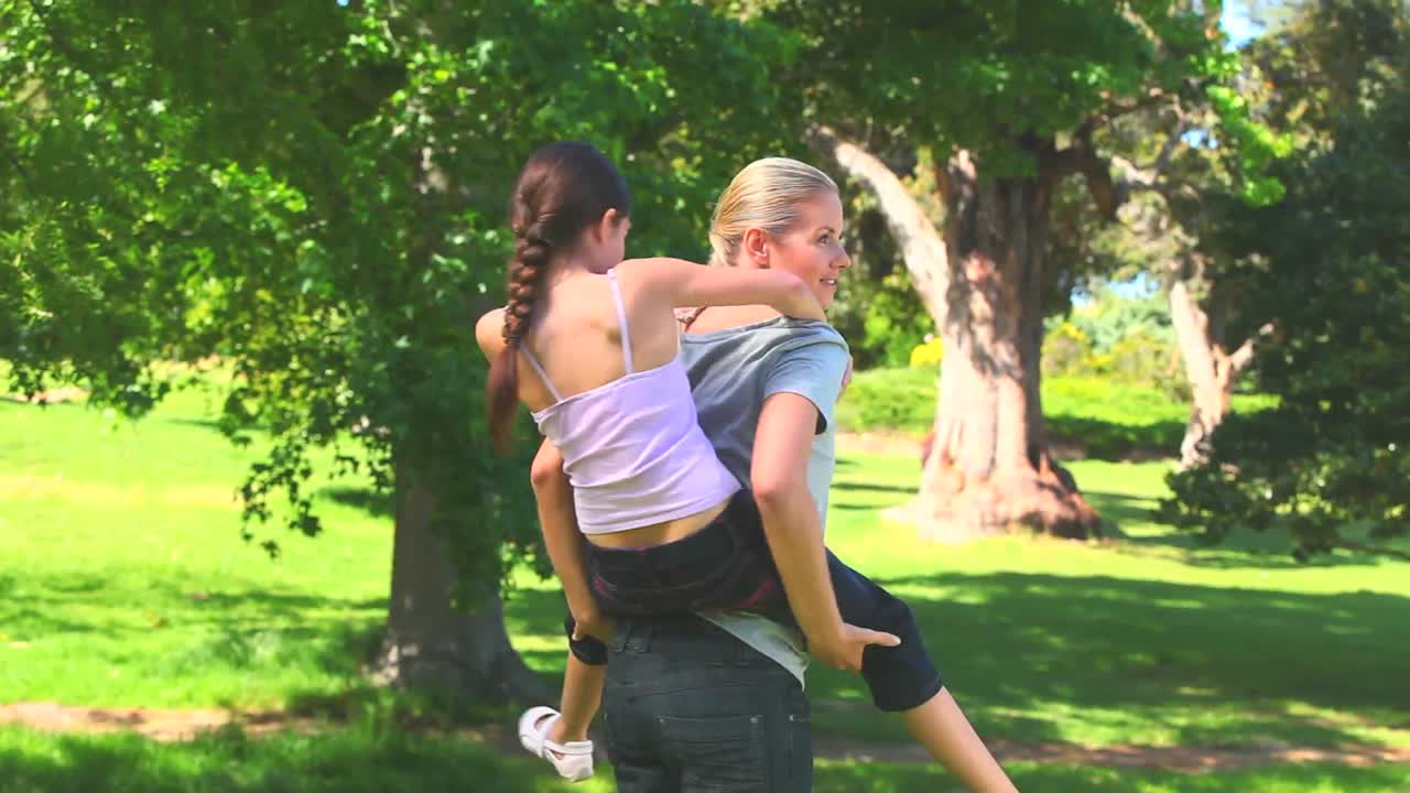 Young mother giving her daughter a piggyback