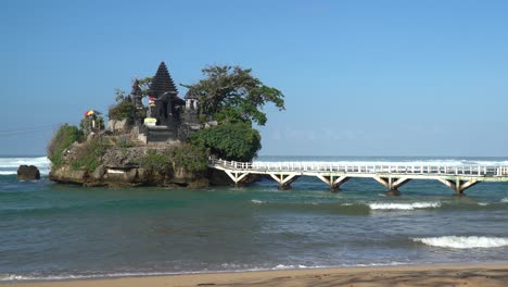 Einsames-Gebäude-Auf-Einer-Strandinsel-Mit-Brücke-Und-Meereswellen,-Die-Am-Horizont-Brechen