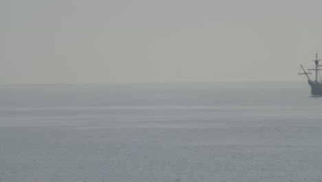 Ferdinand-Magellan-Nao-Victoria-carrack-boat-replica-with-spanish-flag-sails-in-the-mediterranean-at-sunrise-in-calm-sea-entering-the-frame-in-slow-motion-60fps