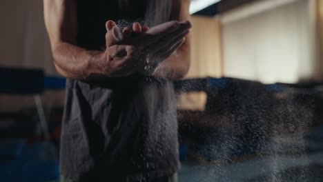 closeup of a man's hands applying chalk before a climbing session