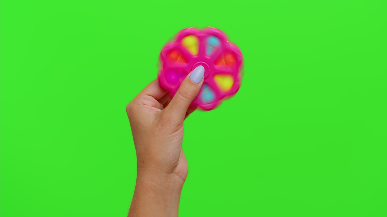 las manos de la niña jugando con pop it spinner juguete sensorial aislado en la llave de croma, alivio de la ansiedad de estrés