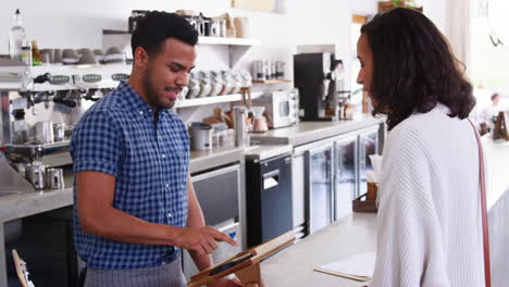 Woman-making-contactless-card-payment-at-a-coffee-shop