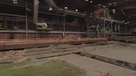 slider footage of machinery in an abandoned brick factory with graffiti and mossy stones