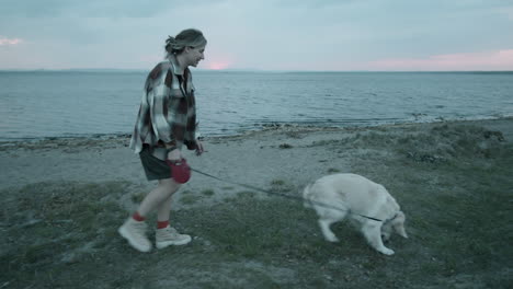 woman walking with dog on lakeside in evening