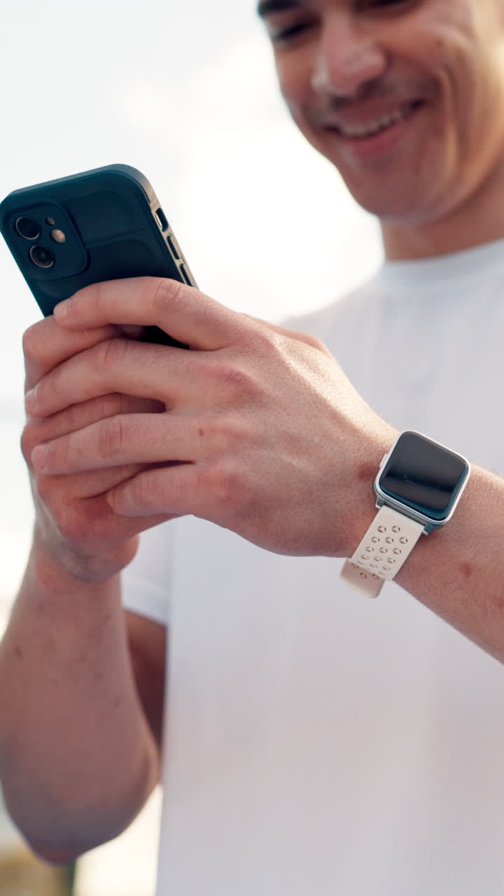 Young Man Smiling While Using Smartphone and Smartwatch