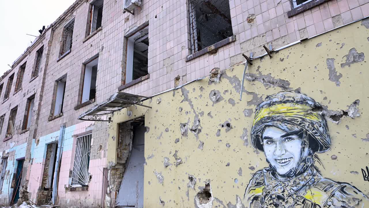 A wide view of a mural of a Ukrainian soldier, surrounded by bullet and shrapnel holes, is seen on a heavily damaged building in Irpin, Ukraine, during the Ukraine-Russia war.