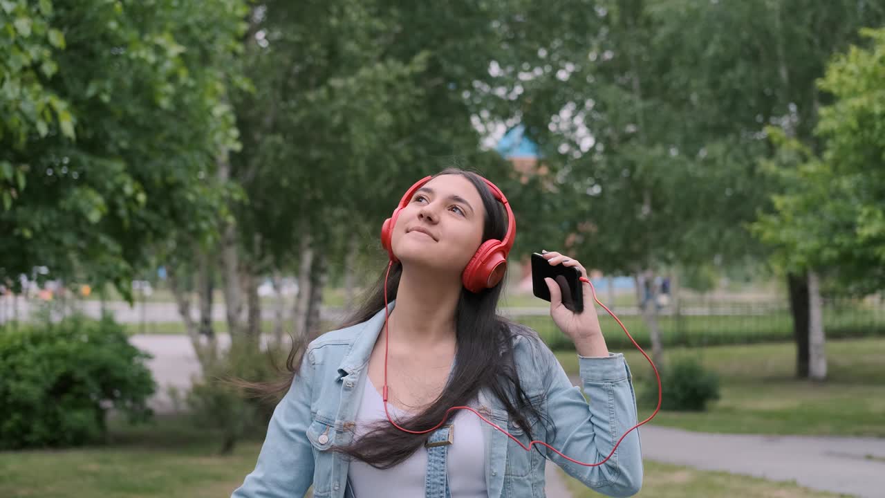 una chica alegre con auriculares camina por la calle