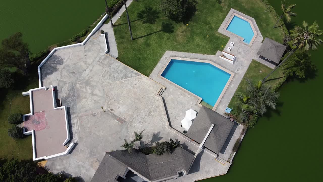 Droneoptagelse af et hus midt i en sø med en pool og palmer i Lima, Peru.