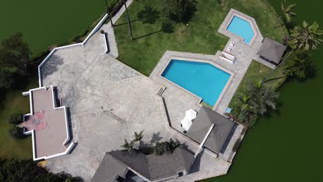 Drone-shot-of-a-house-in-the-middle-of-a-lake-with-a-pool-and-palm-trees-in-the-city-of-Lima-Peru